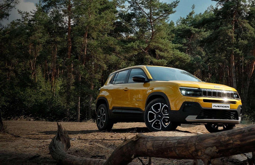 Jeep Avenger e-Hybrid на галявині у сосновому лісі