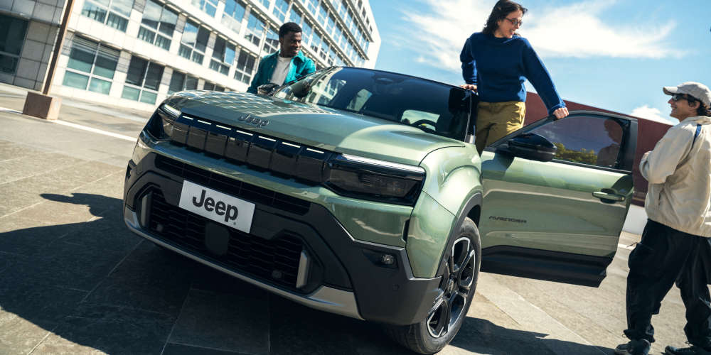 Jeep Avenger зеленого кольору, вигляд спереду, чоловік і жінка поруч