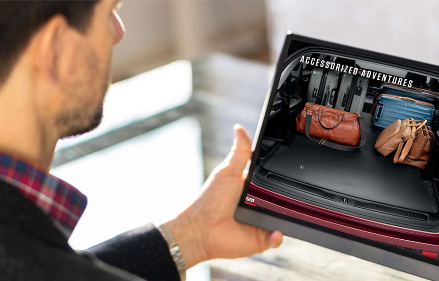 Чоловік тримає в руках планшет з відкритою веб-сторінкою про аксесуари Jeep